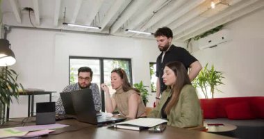 Modern bir ofis ortamında fikir ve stratejileri tartışan dört kişilik bir iş ekibi bir proje üzerinde işbirliği yapıyor..
