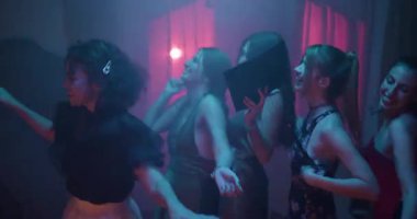 Beş mutlu genç kadın dans edip mezuniyet sonrası partisinde kutlama yapıyor. Bir kız mezuniyet şapkasını elinde tutuyor..