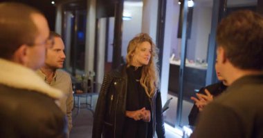 Arkadaşlar sıradan bir buluşmadan, konuşmaktan ve gülmekten zevk alırlar. Sıcak ışıklandırma ve şık kıyafetler rahatlatıcı bir ortam yaratır..