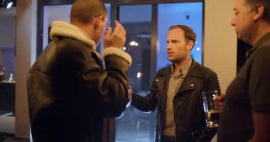 Üç arkadaş gece terasta içki içip sohbet etmekten zevk alır. Sıcak ışıklar ve kahkahalar rahatlatıcı ve keyifli bir atmosfer yaratır..