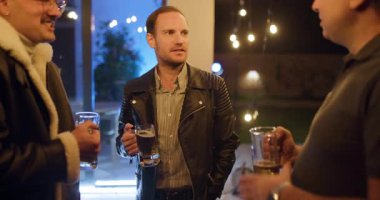 Arkadaşlar gece terasta içki içip sohbet etmekten zevk alıyorlar. Ilık aydınlatma sıcak bir atmosfer yaratır..