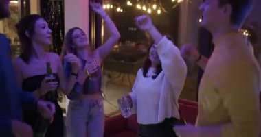 Arkadaşlar kadehlerini kaldırır ve bir doğum günü kutlamasında dans ederler. Renkli parti ışıkları altında içkilerin ve müziğin tadını çıkarırlar..