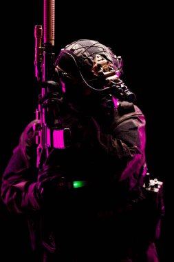 A tactical operator equipped with advanced gear and weaponry, illuminated by striking pink lighting against a dark background. The image highlights themes of readiness, technology, and dedication.