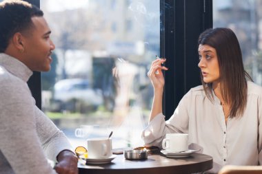 Friends in a restaurant talking smiling and drinking tea. Business colleagues having a meeting after work or during coffee break at a cafe bar.