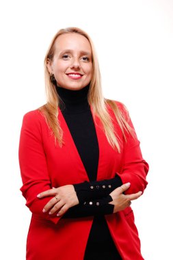 A confident businesswoman stands with her arms crossed, wearing a red blazer over a black top. Her stylish attire and friendly smile reflect her professionalism in a corporate setting.