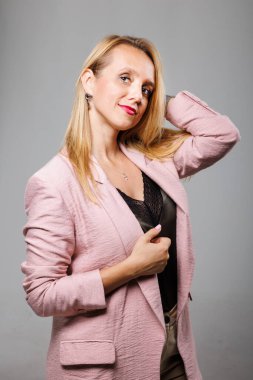 A businesswoman showcases her confidence while adjusting her hair in a chic pink blazer.