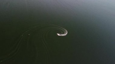 Speedboat makes a circular turn, creating wave patterns on the lakes surface before returning.