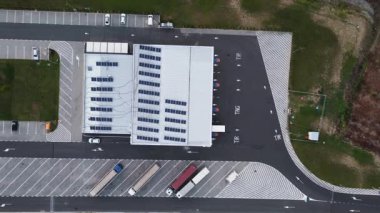Aerial view of a gas station with solar panels on the roof and trucks parked in designated areas.