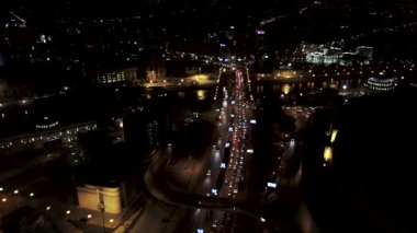 Aerial view of night traffic jam in Skopje, North Macedonia. Cars moving slowly on the bridge over the Vardar River. The Kale Fortress is visible.