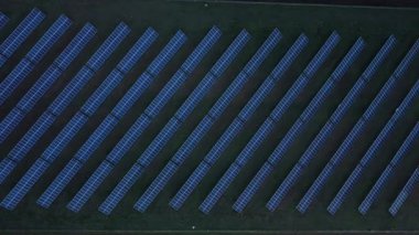 Aerial view of a solar farm at dusk. The camera moves downwards, revealing rows of solar panels. Clean energy, renewable resources.