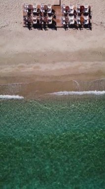 Kafe ya da restoran sandalyeleri ve deniz kenarındaki ahşap bir platformda masalar. Dikey hava görüntüsü boş sahil görüntüsü.