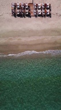 Kafe ya da restoran sandalyeleri ve deniz kenarındaki ahşap bir platformda masalar. Dikey hava görüntüsü boş sahil görüntüsü.