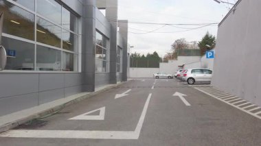 Parking lot with cars and traffic signs. One-way street and no entry signs. Modern building exterior.