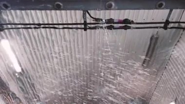 A satisfying moment unfolds as soap sprinklers activate during the car cleaning process. Bubbles fill the air, enhancing the car wash experience at a community location.