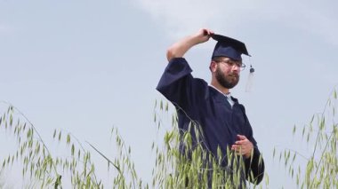 Graduation man alone in a nature against blue sky, throwing the blue cap in air.