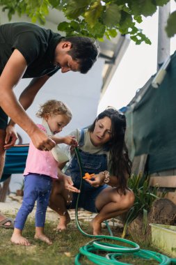 A family enjoys a sunny day while teaching their child simple activities, fostering delightful moments of bonding and learning in a peaceful outdoor environment.