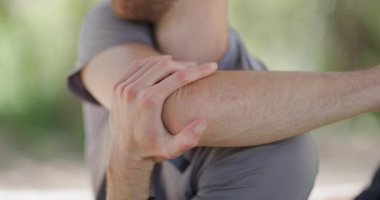 A person demonstrates a series of arm stretches aimed at improving flexibility and mobility in an outdoor location. Warm weather and natural surroundings make for a perfect backdrop.