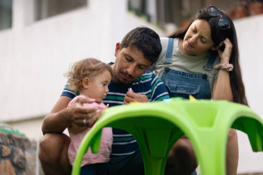 A young family features parents and their child creating art outside, symbolizing family bonds and creativity.