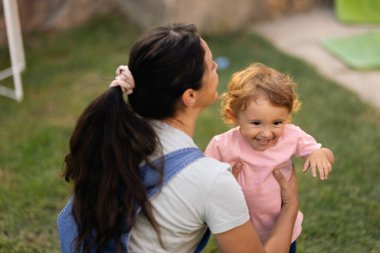 Warm moment of a woman spending time with her happy child outside, embracing joy and family connection.