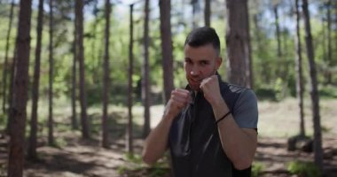 A person practices martial arts techniques in a serene forest environment. The lush greenery and tall trees provide a perfect backdrop for developing skills and discipline.