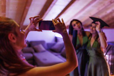 Friends commemorating achievements with photos and warmth, highlighting academic milestones in a joyful atmosphere.