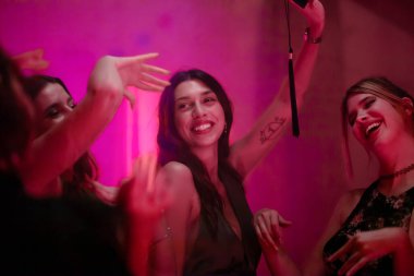 A group of friends enjoying a party celebration, smiling and having fun with vibrant lighting. The mood is lively and filled with joy and togetherness during this festive moment among close companions