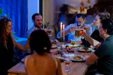 A group of friends gathers at a warmly lit table to share a delightful dinner and drinks, creating a relaxed and joyful atmosphere, fostering camaraderie and memorable moments.