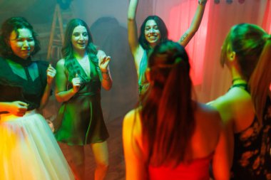 A group of women dancing and celebrating cheerfully at a social gathering in a vibrant setting, enjoying an engaging and spirited evening and camaraderie.