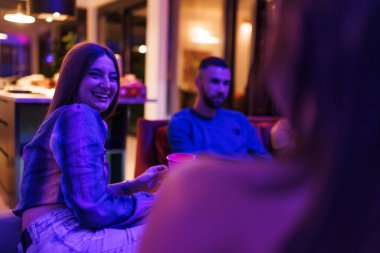 A friendly gathering of young individuals sharing an enjoyable moment in a cozy home, emphasizing the warmth and camaraderie of the setting.