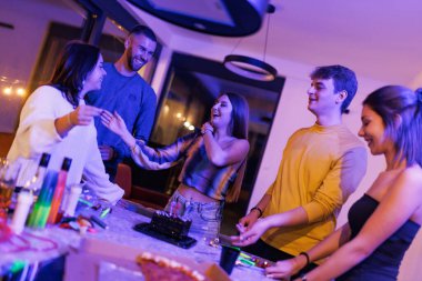 A group of friends enjoying a celebratory and lively moment with smiles, laughter, and good company in a cozy, illuminated indoor setting.