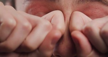 A close-up image capturing a person covering their eyes with hands, depicting feelings of fatigue, stress or headache.