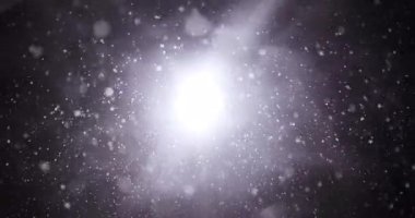 Snowflakes falling at night against a bright light. Perfect for winter, Christmas, or holiday-themed projects.