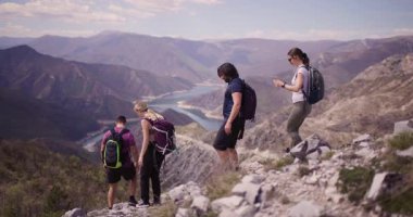 Bir grup arkadaş sakin göle bakan dağlık bir alanda yürüyüş yapıyorlar. Manzaradan hoşlanırlar, sohbet ederler ve doğanın huzurunu birlikte yaşarlar..