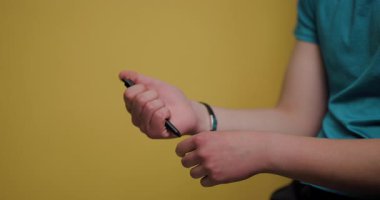 A man is engaged in using a smartphone, absorbed in what he is doing. He appears relaxed and comfortable while seated in a brightly colored space. The background enhances the casual vibe.