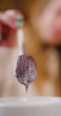 Woman dipping a cake pop into melted white chocolate. Close up of a cake pop covered in chocolate.
