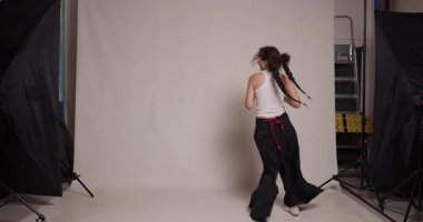 A dynamic image capturing a young Kazakh woman as she practices dance steps in a professional studio, under soft studio lighting.