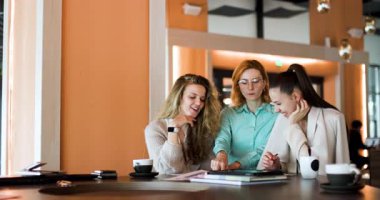 In a lively cafe, a group of businesswomen engage in a spirited discussion, exchanging ideas and insights while sipping coffee. Their camaraderie shines through as they collaborate.