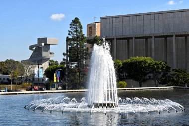 LOS ANGELES, CALIFORNIA - 18 NOV 2024: Fountain at the John Ferraro Building with the Ahmanson Theatre, LA Cathedral and School of Visual and Performing Arts in the background. clipart