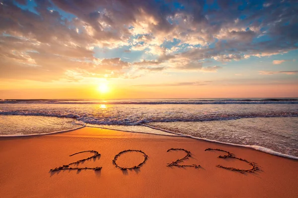 Happy New Year 2023 ocean sunrise on the beach sand concept