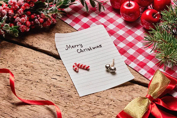 Merry Christmas text card or letter on wooden desk with holiday new year decoration.