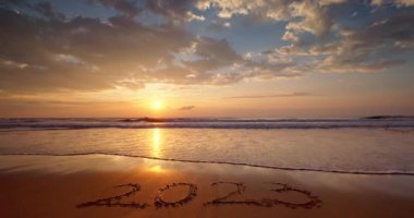 Seascape sunrise and text on beach sand new year 2023. Paradise island beach 4K video