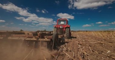 Farmer in tractor harrowing the ground in a agricultural field. Cultivate, agriculture and farming concept in 4k video
