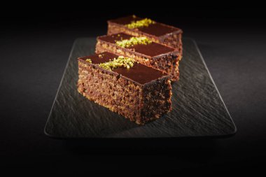 Chocolate cake with walnuts and pistachio isolated on black background. Pastry from homemade bakery
