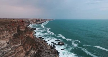 Bulgaristan ve Karadeniz kıyısı. Kamen Bryag 'daki kayalık kayalıklar ve çarpan deniz dalgaları, dramatik 4K video