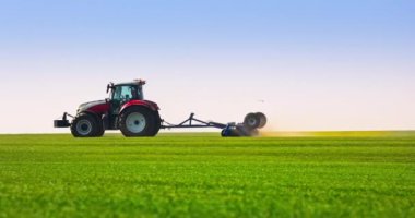 Tractor with a roller tillage working on fresh green spring field, 4k video. Soil rolling supports germination and is the basis for good harvesting