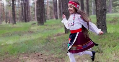 Bulgarian girl in traditional folklore costume running in forest of majestic mountain, 4k slow motion video. Bulgaria nature