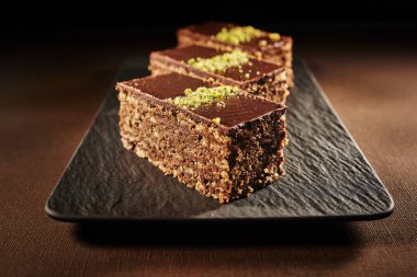 Chocolate cake with walnuts and pistachio isolated on black background. Pastry from homemade bakery