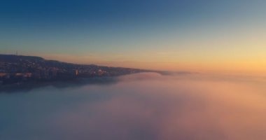 Gökyüzü bulutları üzerinde uçuyor ve şehre ve sahile doğru hava manzarası var. Bulgaristan 'ın Varna kentinde günbatımı, 4k video