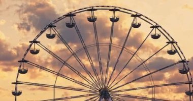 Dönen Karnaval Dönme dolabı lunaparkta gün batımı manzaralı gökyüzü bulutlarına karşı