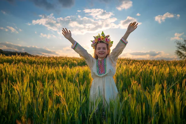 小麦畑で夕日の間に花の連句 伝統的なブルガリアの刺繍と民族の民俗衣装を持つ美しい若い女の子 — ストック写真